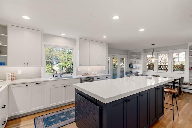 kitchen with open shelves, a sink, light countertops, light wood-style floors, and white cabinetry