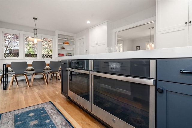 kitchen featuring recessed lighting, white cabinets, light wood finished floors, and decorative light fixtures