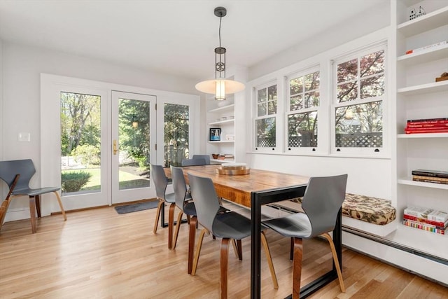 dining area featuring built in features, a baseboard radiator, and light wood-style flooring