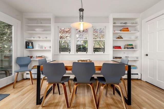 dining space with a healthy amount of sunlight, light wood-style floors, and built in shelves