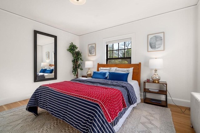 bedroom featuring wood finished floors, baseboards, and radiator heating unit