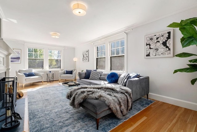 living area featuring crown molding, radiator, baseboards, a fireplace with flush hearth, and wood finished floors