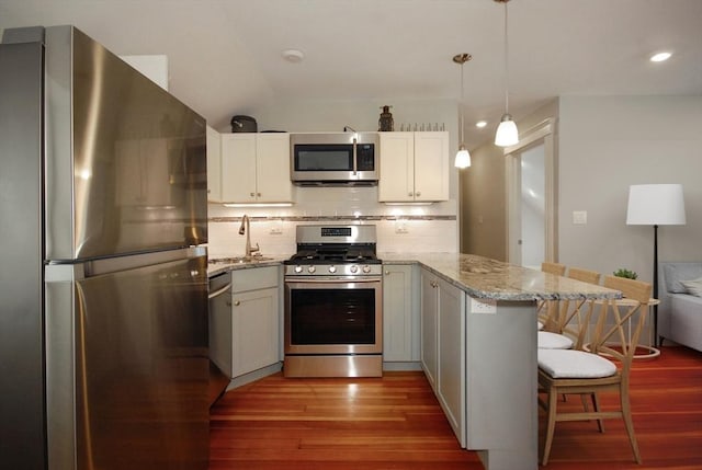 20 Beechwood Ave Unit B, Watertown, MA 02472 - kitchen featuring stainless steel appliances, a peninsula, a sink, wood finished floors, and backsplash