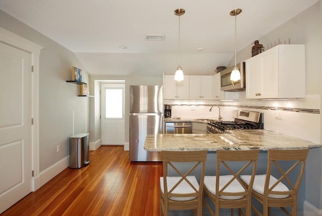 20 Beechwood Ave Unit B, Watertown, MA 02472 - kitchen featuring appliances with stainless steel finishes, a peninsula, light stone countertops, decorative backsplash, and lofted ceiling