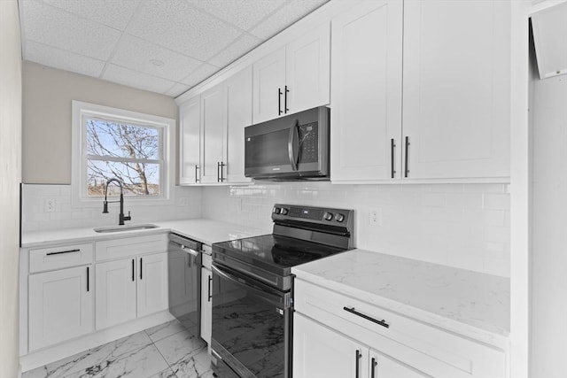 kitchen with marble finish floor, tasteful backsplash, appliances with stainless steel finishes, white cabinets, and a sink