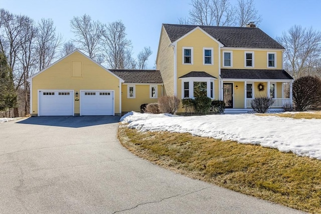 view of front of property featuring a porch, a chimney, an attached garage, and a shingled roof