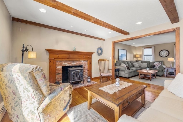 living room with beamed ceiling, wood finished floors, a wood stove, and recessed lighting