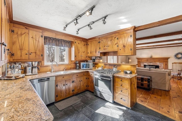 kitchen featuring appliances with stainless steel finishes, a sink, and brown cabinets