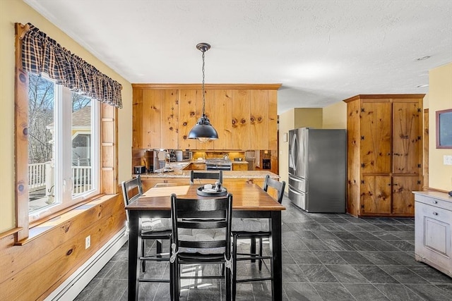 kitchen featuring decorative light fixtures, stainless steel appliances, a baseboard radiator, light countertops, and wood walls