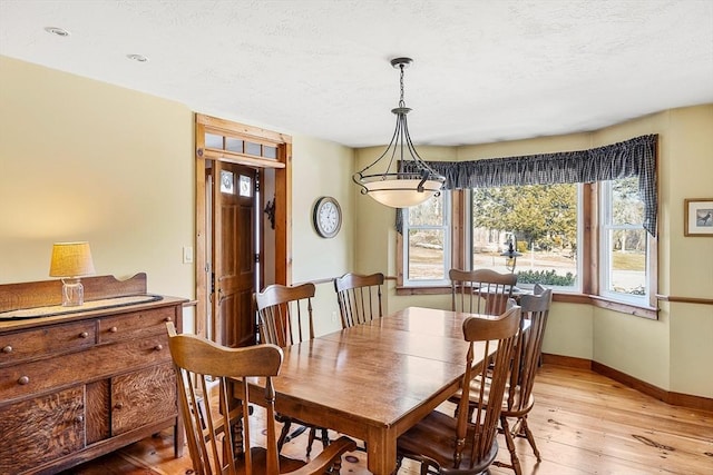 dining room featuring light wood-type flooring, baseboards, and a textured ceiling