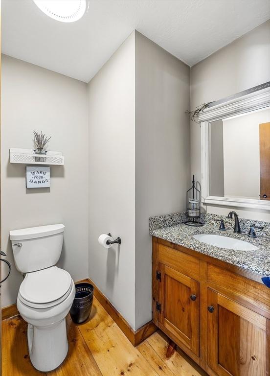 bathroom featuring vanity, wood finished floors, toilet, and baseboards