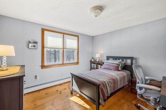 bedroom featuring a baseboard heating unit and light wood-style floors