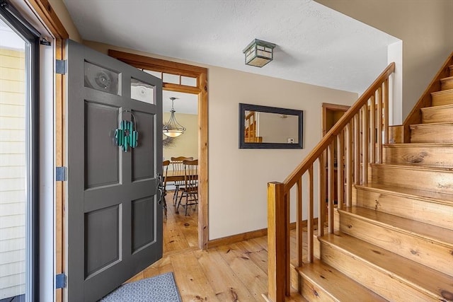 foyer entrance featuring stairs, light wood-style flooring, and baseboards