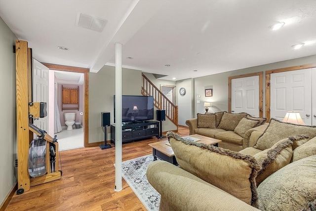 living room with stairs, baseboards, visible vents, and light wood-style floors