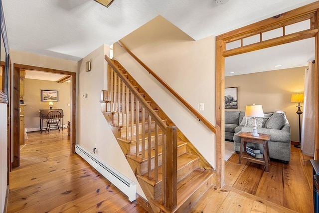 stairs featuring baseboard heating and wood-type flooring