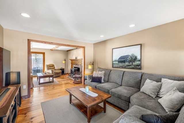 living room with light wood-type flooring, a fireplace, baseboards, and recessed lighting