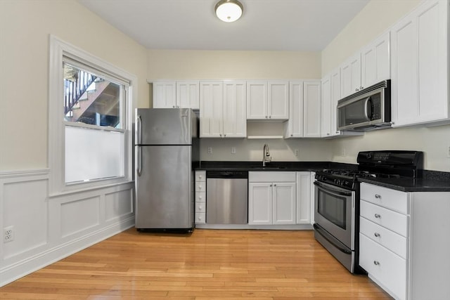 16 Emerson St Unit 1, Boston, MA 02127 - kitchen with stainless steel appliances, dark countertops, white cabinets, light wood finished floors, and wainscoting