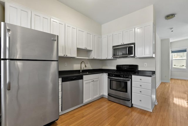16 Emerson St Unit 1, Boston, MA 02127 - kitchen with appliances with stainless steel finishes, light wood-type flooring, white cabinetry, and dark countertops