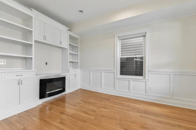 16 Emerson St Unit 1, Boston, MA 02127 - unfurnished living room with light wood-style floors, a glass covered fireplace, a wainscoted wall, a decorative wall, and ornamental molding