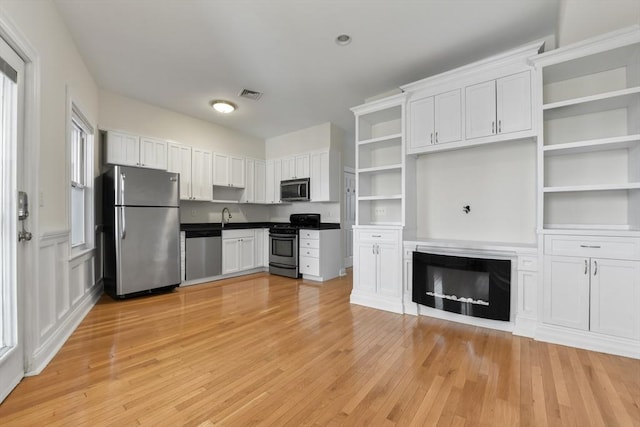 16 Emerson St Unit 1, Boston, MA 02127 - kitchen with stainless steel appliances, open shelves, white cabinets, light wood-style flooring, and dark countertops