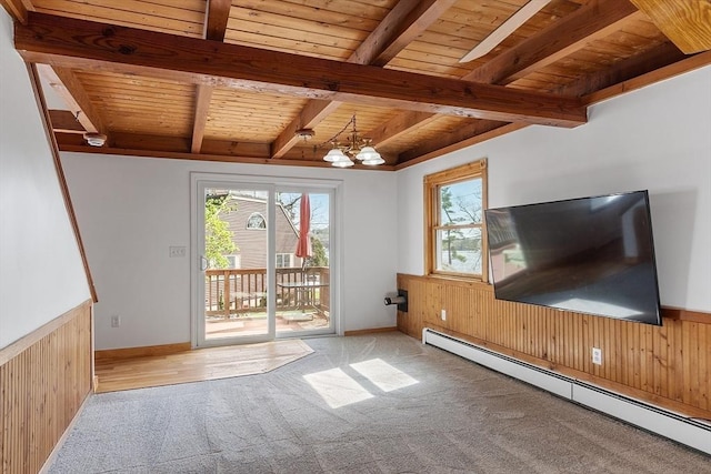 unfurnished living room with wood ceiling, wainscoting, carpet floors, a baseboard radiator, and wooden walls