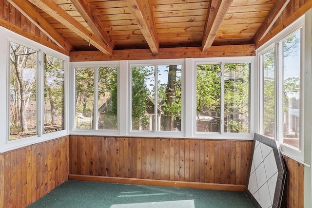 unfurnished sunroom featuring wooden ceiling, wood walls, lofted ceiling with beams, and carpet