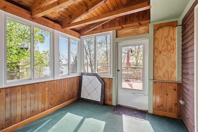 unfurnished sunroom featuring plenty of natural light, lofted ceiling with beams, wood ceiling, and wooden walls
