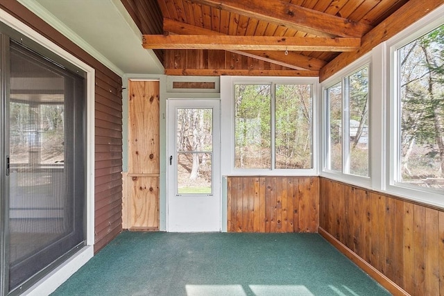 unfurnished sunroom with wooden walls, carpet flooring, wooden ceiling, and vaulted ceiling with beams
