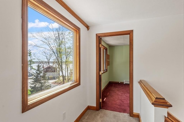 corridor with baseboards, carpet flooring, and a baseboard heating unit