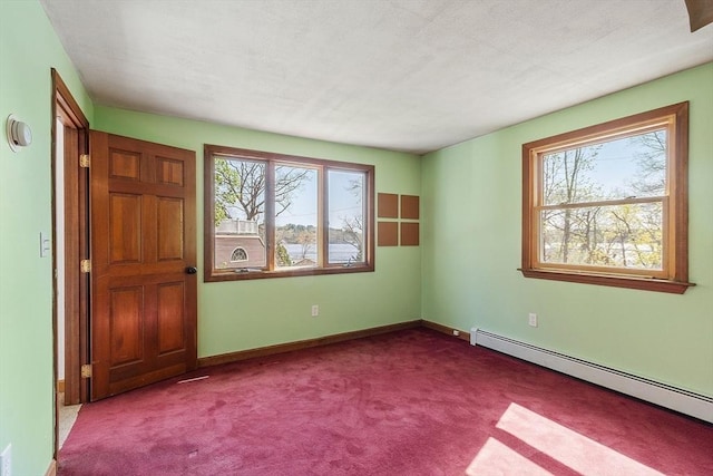 spare room featuring baseboards, carpet, and a baseboard heating unit