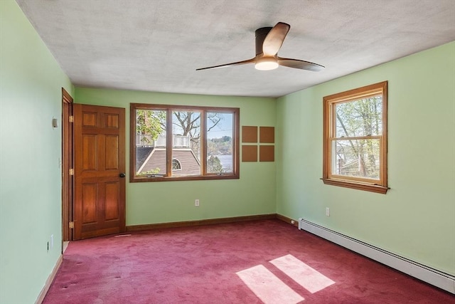 spare room featuring baseboards, a baseboard radiator, a ceiling fan, and carpet flooring