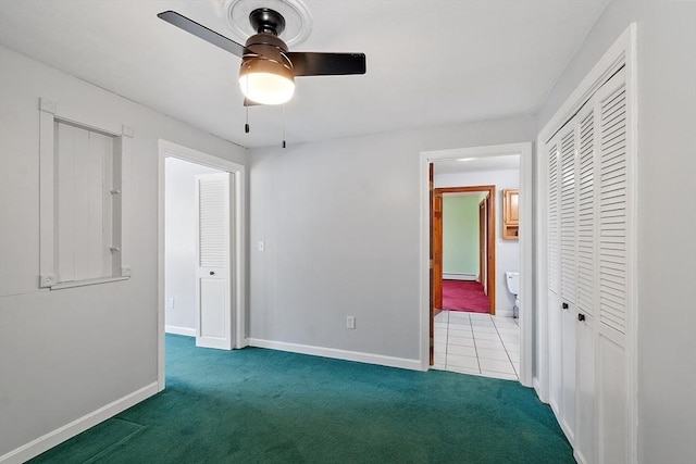 unfurnished bedroom with carpet flooring, baseboards, ceiling fan, and ensuite bathroom