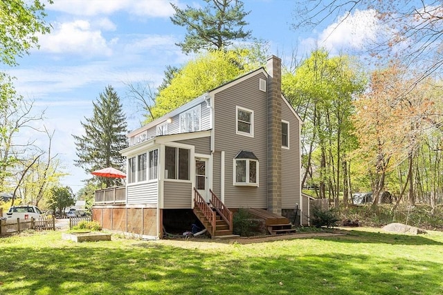 back of property featuring a lawn, fence, a chimney, and a sunroom