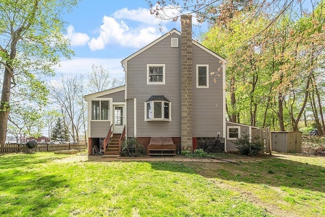 back of house with a sunroom, fence, a yard, and a chimney