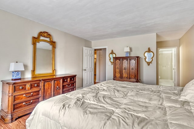 bedroom with light hardwood / wood-style flooring and ensuite bath