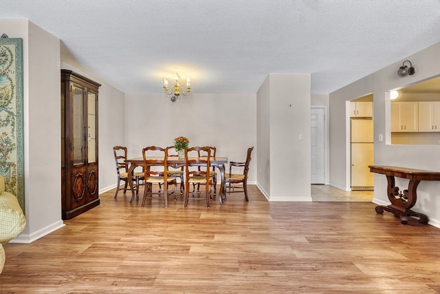 dining room featuring light hardwood / wood-style flooring, a textured ceiling, and a chandelier