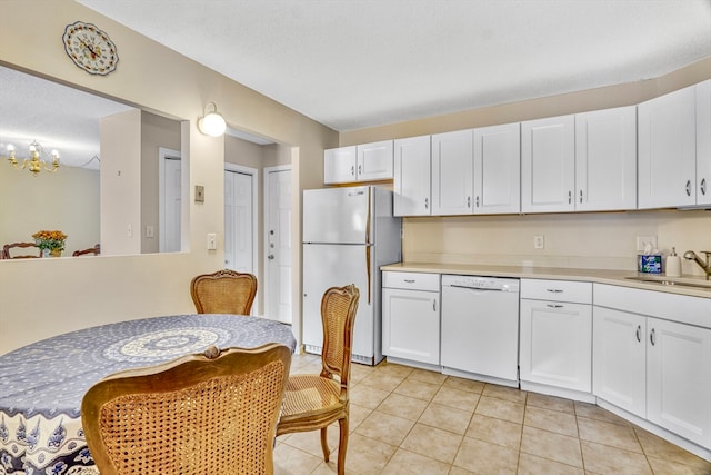 kitchen with sink, an inviting chandelier, light tile patterned floors, white cabinets, and white appliances