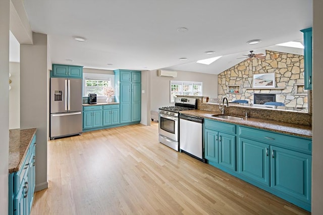 28 Ridge St, Arlington, MA 02474 - kitchen with appliances with stainless steel finishes, ceiling fan, blue cabinets, a stone fireplace, and light wood-type flooring
