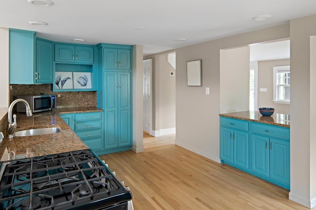 28 Ridge St, Arlington, MA 02474 - kitchen with stainless steel microwave, light wood finished floors, and dark stone counters