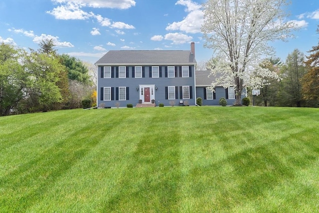colonial inspired home featuring entry steps, a chimney, and a front yard