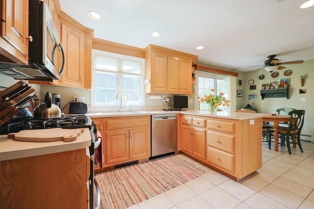 kitchen with a sink, appliances with stainless steel finishes, light brown cabinets, and a peninsula