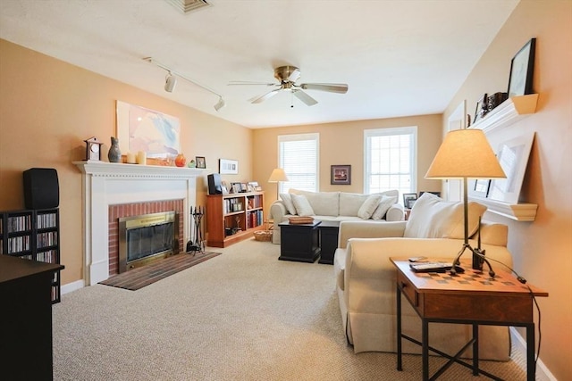 living area with carpet floors, a ceiling fan, a brick fireplace, and rail lighting