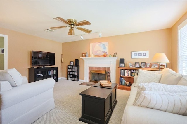 living area with ceiling fan, track lighting, light carpet, a fireplace, and visible vents