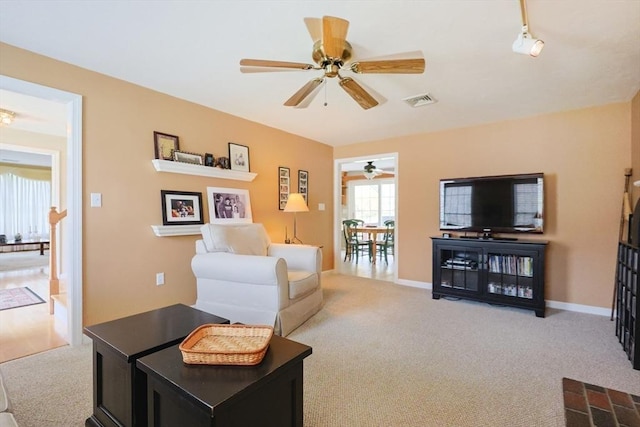 carpeted living room featuring visible vents, a ceiling fan, and baseboards