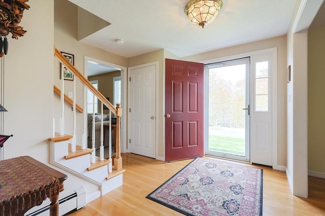 foyer with light wood-style floors, baseboards, stairway, and baseboard heating