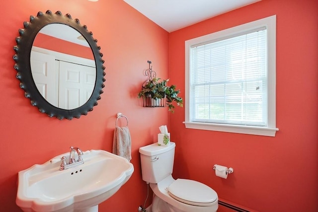 bathroom with a sink, baseboard heating, and toilet