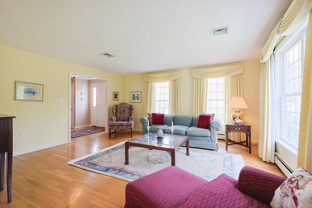living room with visible vents, a baseboard radiator, light wood-style floors, and baseboards