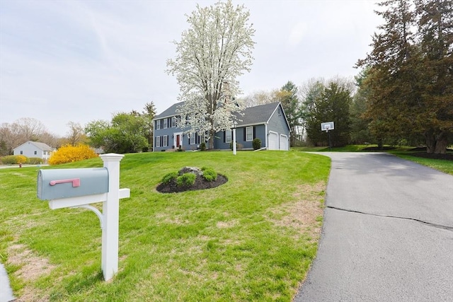 colonial inspired home with driveway, a front yard, and a garage