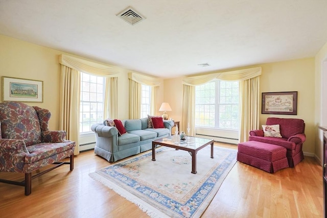 living room featuring a baseboard heating unit, visible vents, and wood finished floors