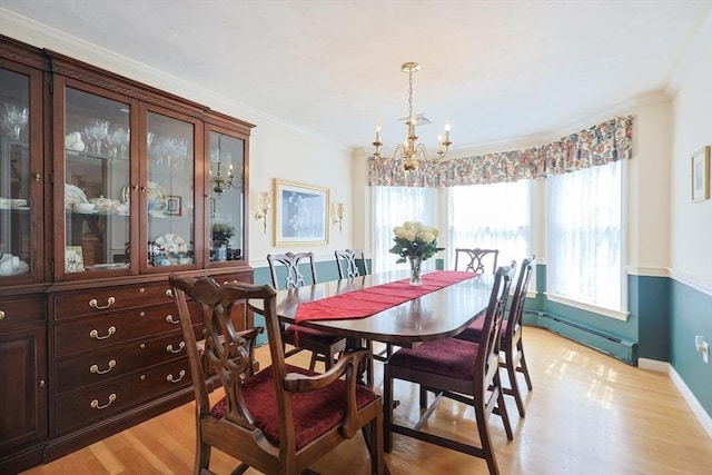 dining space featuring an inviting chandelier, baseboards, light wood-type flooring, a baseboard heating unit, and ornamental molding